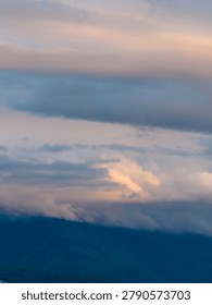 Soft pastel clouds and mist settle over a peaceful mountain range at sunset near Chilliwack, British Columbia, Canada.