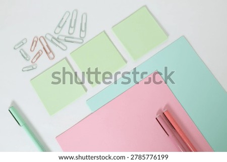 Soft pastel flat lay composition with sticky notes, paper clips, pens and notebooks on clean background, education and organization concept.