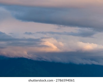 Soft pastel sunset clouds hover above a mountain ridge near Chilliwack, British Columbia, Canada, evoking calm and atmosphere.
