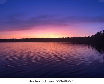 Soft Pastel Sunset Over a Calm Lake with Rippling Water and Silhouetted Trees - Powered by Shutterstock