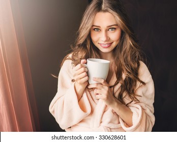 Soft photo of fresh young woman in pink tender bathrobe drink tea and smiling. Pretty girl with perfect  wavy hairs enjoying  early  sunny morning. - Powered by Shutterstock