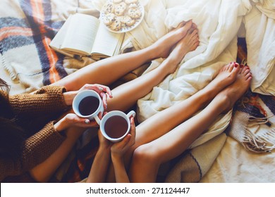 Soft photo of two  sisters  on the bed with old books and cup of tea in hands wearing cozy sweater , top view point. Two best friends enjoying morning. - Powered by Shutterstock