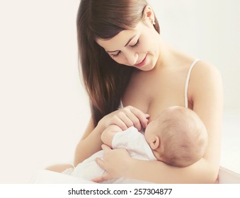 Soft photo young mother feeding breast her baby at home in white room