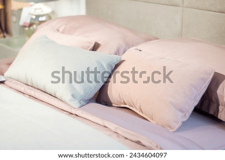 Soft pillows on a large bed in pastel colors close up