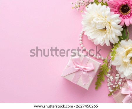 A soft pink flat lay featuring elegant white and pink flowers, a pearl necklace, and a gift box with a satin ribbon—perfect for celebrating a special woman