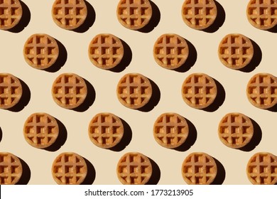 Soft round fried waffles on a beige background. Monochrome pattern with hard shadows.