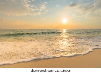 Soft Sea Waves And Bubbles On The Beach With Sunset Sky Background.