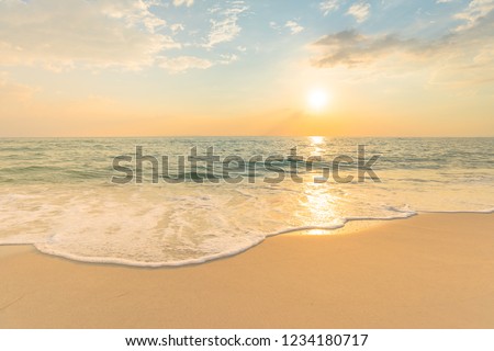 Soft sea waves and bubbles on the beach with sunset sky background.