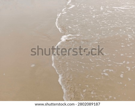 Soft sea waves reaching the sandy shoreline, creating a peaceful coastal background. Perfect for travel, summer, relaxation, nature, tourism, and marine-themed designs.