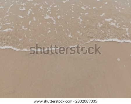 Soft sea waves reaching the sandy shoreline, creating a peaceful coastal background. Perfect for travel, summer, relaxation, nature, tourism, and marine-themed designs.