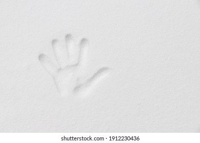 Soft selective focus of hand mark on white fluffy snow surface, Left handprint on the stain of snow in winter, Abstract texture background.