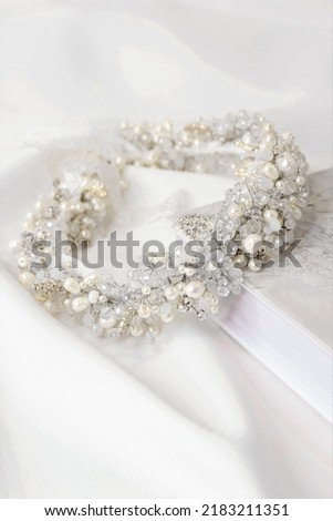 Soft selective focus image of bridal crystal and pearl handmade hairband on white silk light background. Wedding concept
