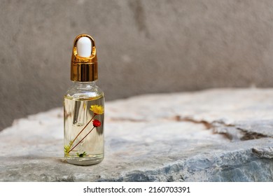 Soft selective focus Layout of glass dropper bottle with dried flowers and herbs in the phial on natural stone podium background. Eco-cream, serum, cosmetics, massage oil. Front view, Copy Space