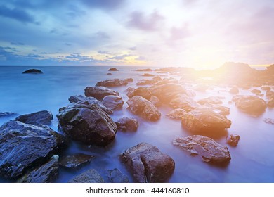 Soft setting sun and wave with sunset over sea and rocks coast