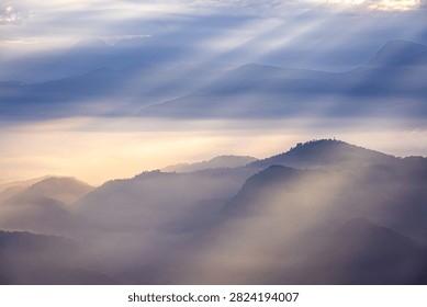 Soft sunbeams filter through mist above layered mountain valleys in Nantou, Taiwan.