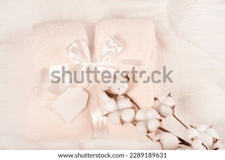 soft surface of a fluffy beige plaid with a mockup sign for an inscription, with a gift ribbon and a branch of cotton. fluffy plaid in color of the year 2026 CLOUD DANCER 11- 42011,  pantone  