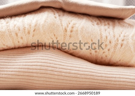 Soft sweaters and blouses folded into a pile.