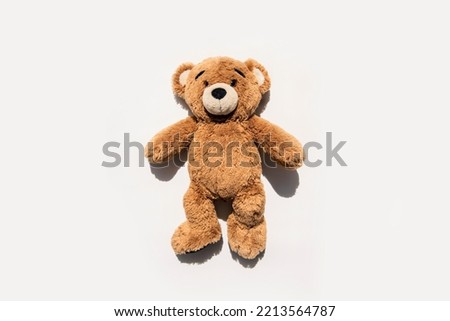 Soft toy bear lies on a white background. Top view, flat lay.