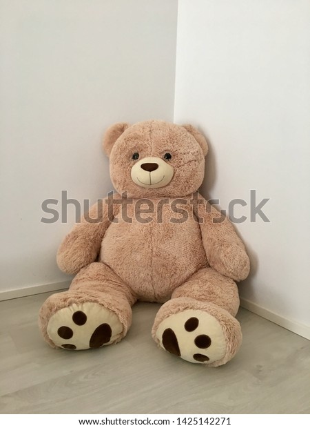 Soft toy a bear sits. Beige Big\
teddy bear in the interior. An unexpected surprise for a child or\
girl. Life-size doll. Fluffy friend. Best\
gift.beige\
