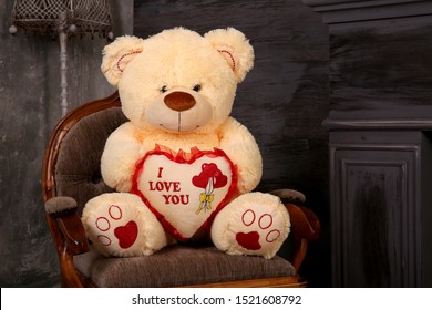 Soft toy bear sits on a chair. Large teddy fur bear in the interior. An unexpected surprise gift for a child or girl.