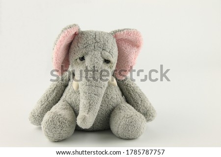 soft toy elephant sitting down, isolated on white background with copy space
