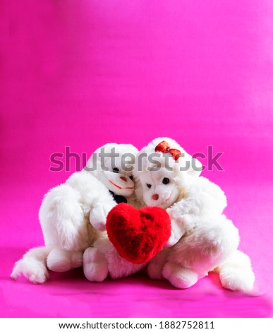 Soft toy monkeys holding a heart on a pink background. A symbol of love. valentine's day