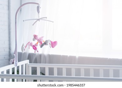 Soft Toys Hanging Over Crib In Nursery Near Window