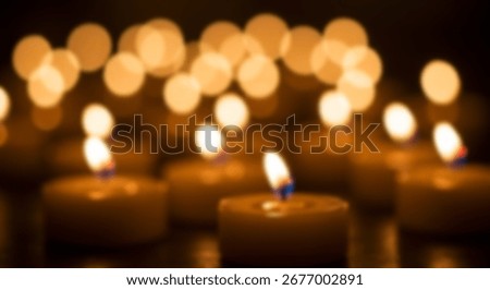 Soft, warm light emanates from numerous tea light candles, focused on a few in the foreground, with a blurred background of glowing circles.