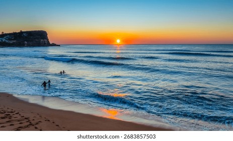 Soft waves roll ashore beneath a blush-toned sky, as sunrise unfurls over Avalon Beach on Sydney’s Northern Beaches.