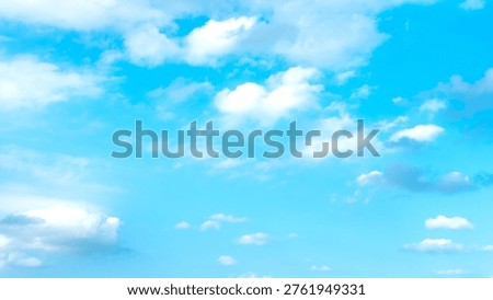 Soft white clouds drift across a bright blue sky