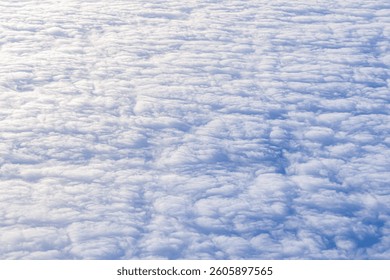 Soft, white clouds drift gracefully in a clear blue sky, enhancing the beauty of nature. Background white clouds top view a smooth carpet of clouds
