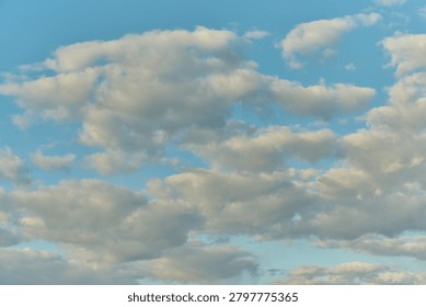 Soft, white clouds float gracefully in a serene blue sky during the late afternoon. The peaceful scene evokes a sense of calm and tranquility, inviting deep breaths and daydreams.