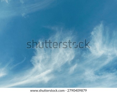 Soft white clouds streaking across a clear blue sky on a bright sunny day. Ideal for weather reports or peaceful background imagery.