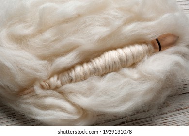 Soft White Wool And Spindle On Wooden Table, Closeup