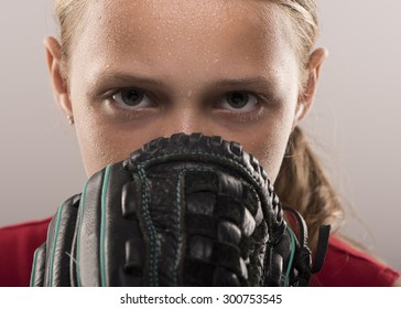 Softball girl with sweat looking from behind a mitt