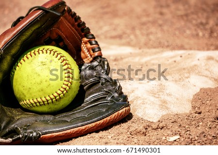 Softball and glove in front of the base.