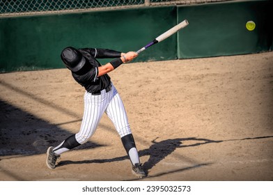 A Softball Player Is Batting And Makes Contact With The Baseball - Powered by Shutterstock