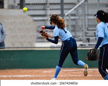Softball player throwing the ball to first base for an out