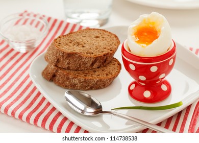 Soft-boiled egg in a red egg cup and whole grain bread - Powered by Shutterstock