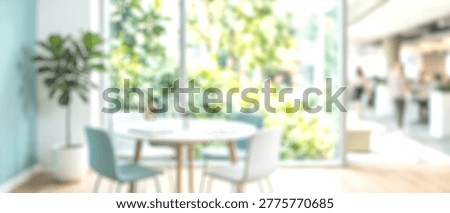 A soft-focus image capturing the bright and airy ambiance of a contemporary cafe or restaurant, featuring a table and chairs with a large window overlooking vibrant green foliage, perfect for a seren.