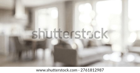 A softly blurred interior scene showcasing a modern living room with comfortable seating and natural light streaming through large windows.