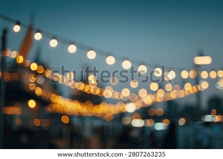 Softly blurred string lights create a magical bokeh effect against a twilight sky, suggesting a festive outdoor gathering.