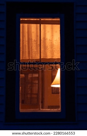 Softly lit, soft-focus window of a farmhouse, lit from within at night. Lampshade, thin curtains, amber glow. Painterly, vintage mood.
