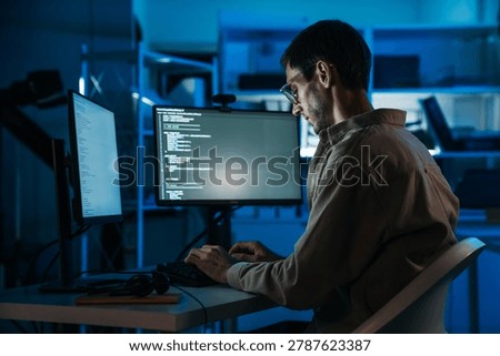 Software developer coding application interface in modern programming workspace while working on backend development and computer engineering projects during night shift.