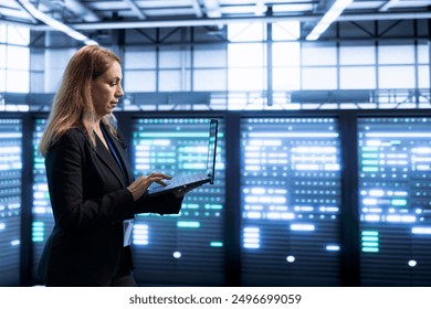 Software developer in data center implementing backup solutions to protect against data loss using laptop, ensuring efficient recovery processes. Woman in server room resolving technical issues - Powered by Shutterstock