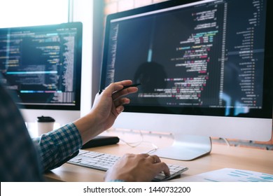 Software developer holds the pen pointing to the computer screen and is analyzing the code. - Shutterstock ID 1440732200