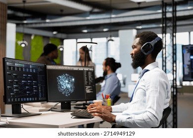 Software developer leverages AI language model assistance while coding in artificial intelligence company office. African american startup admin integrates LLM chatbot suggestions into code editor