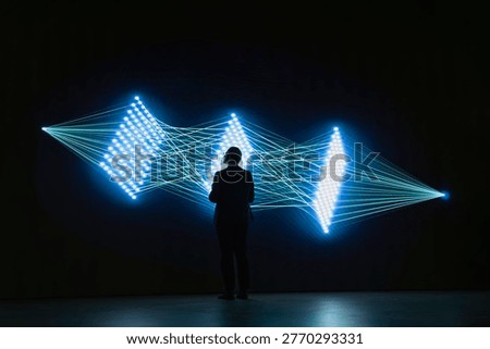 Software developer monitors AI model connections using visual interface. Computer scientist studies artificial intelligence neural network synapses on digital wall to understand processing algorithms
