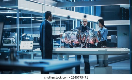 Software Developer, Project Manager and Machinery Operators Collaborate on a Prototype Turbine Engine, Standing with Laptop Computer in Scientific Technology Lab. Team Developing a New Electric Motor.