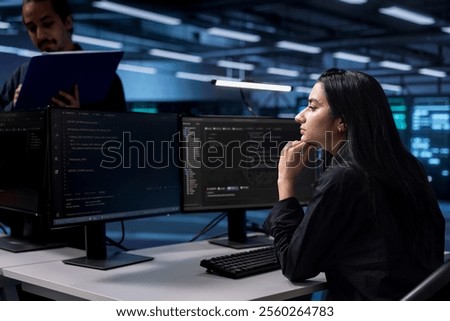 Software developer reconfiguring server farm to optimize it for data processing requirements of customers. Indian woman ensuring data center equipment operates efficiently
